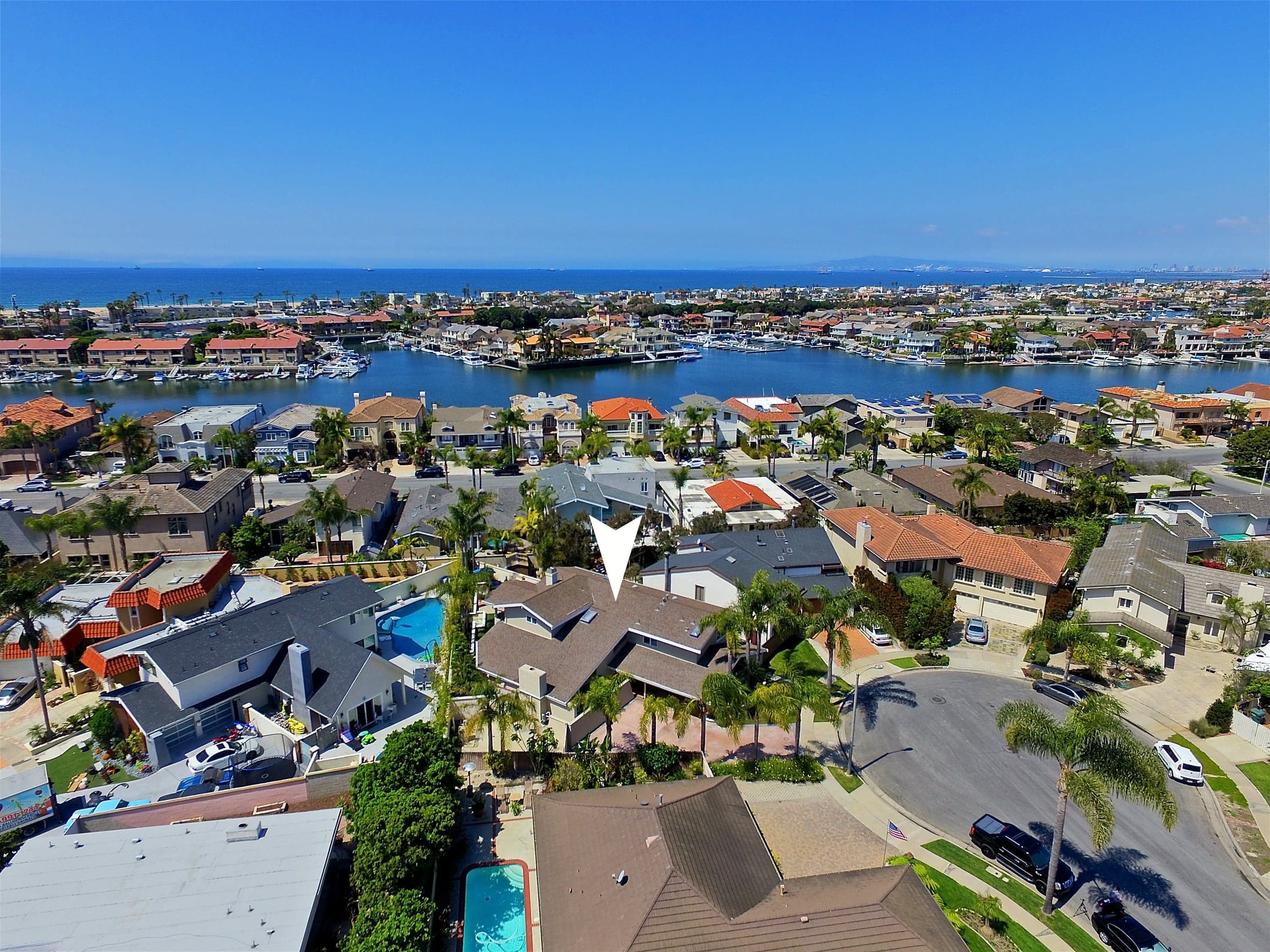 Aerial drone view over the waterfront homes and private boat docks of Huntington Harbour, the kind of cinematic marketing Ratowsky Group runs on every luxury listing.