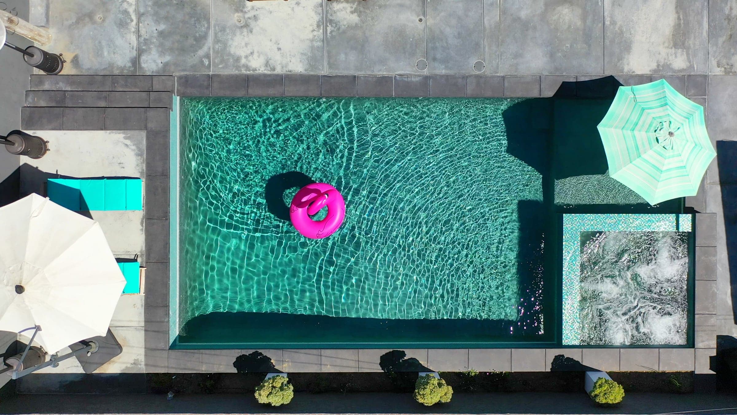 Overhead drone view of a coastal luxury home's pool and grounds.