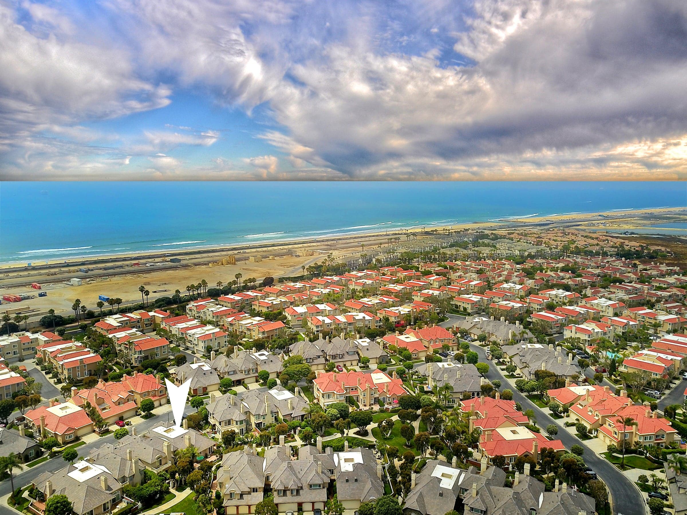 Aerial of the Seacliff neighborhood in Huntington Beach, red-tile-roof homes stretching to the beach and Pacific.