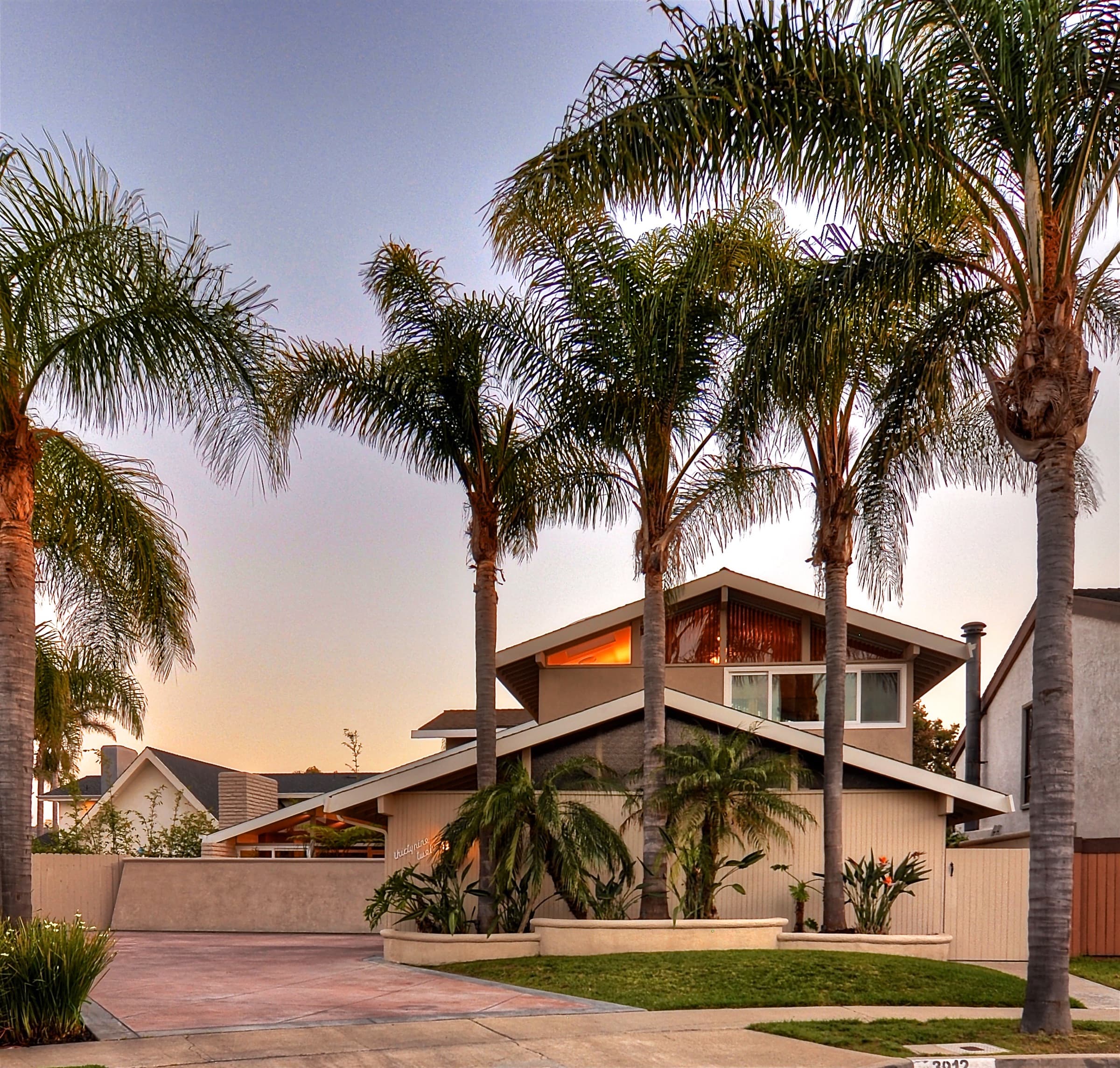 Twilight exterior of a Huntington Harbour home framed by palms, a Ratowsky Group listing.