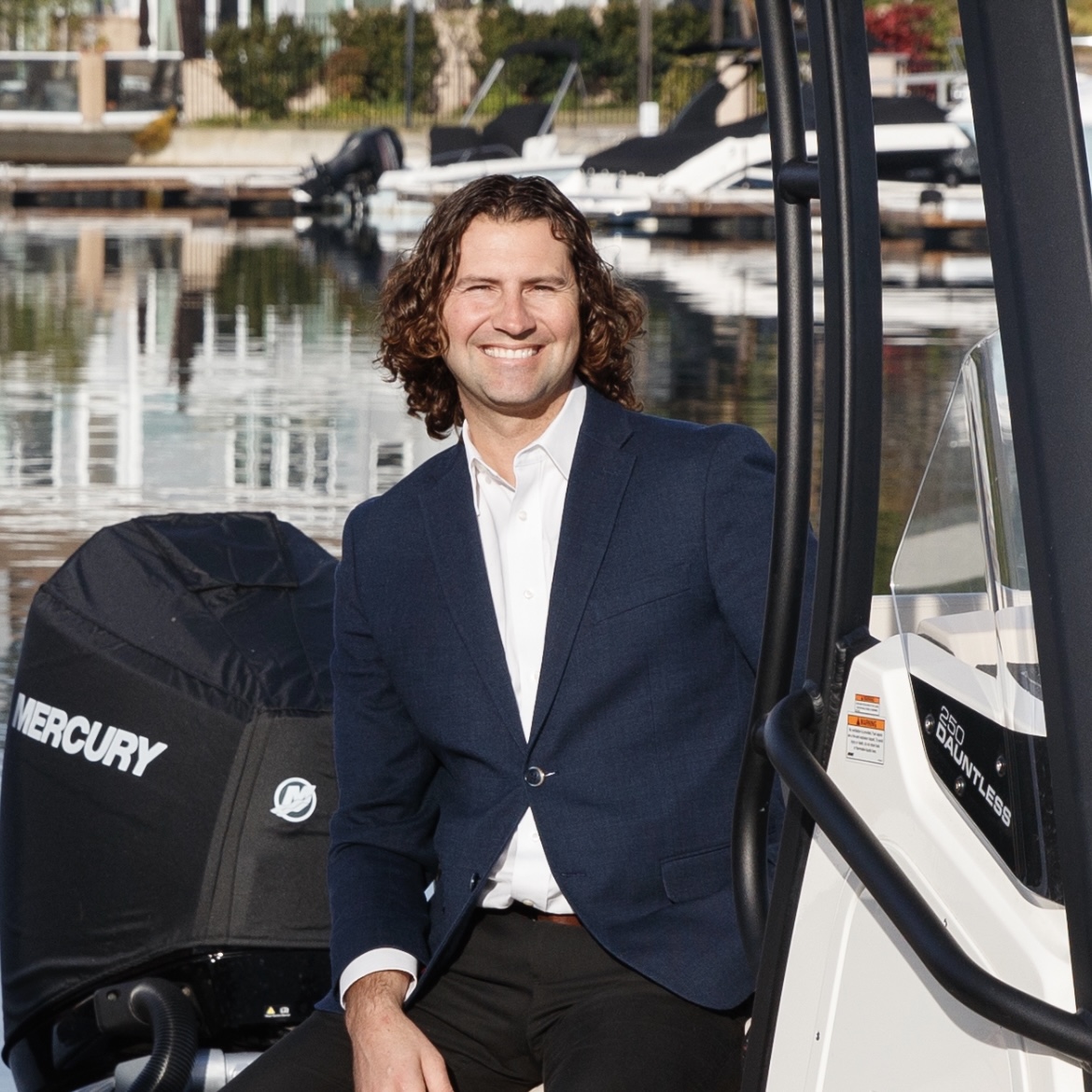 Justin Ratowsky seated on a boat in Huntington Harbour, third-generation California Realtor® and Huntington Beach local with Ratowsky Group at Compass.