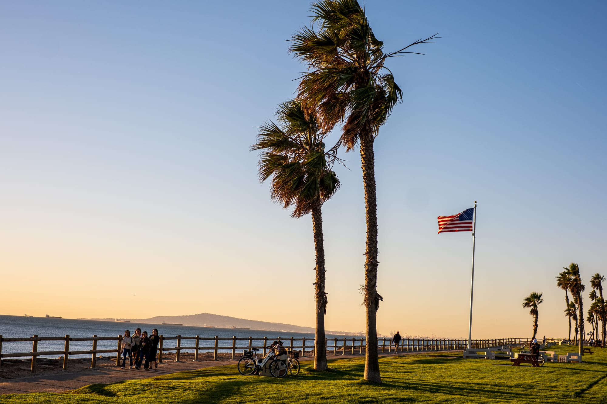 Palm trees and an American flag on the oceanfront bluff at Patriot Point, near Pacific Coast Highway and Goldenwest Street at sunset.