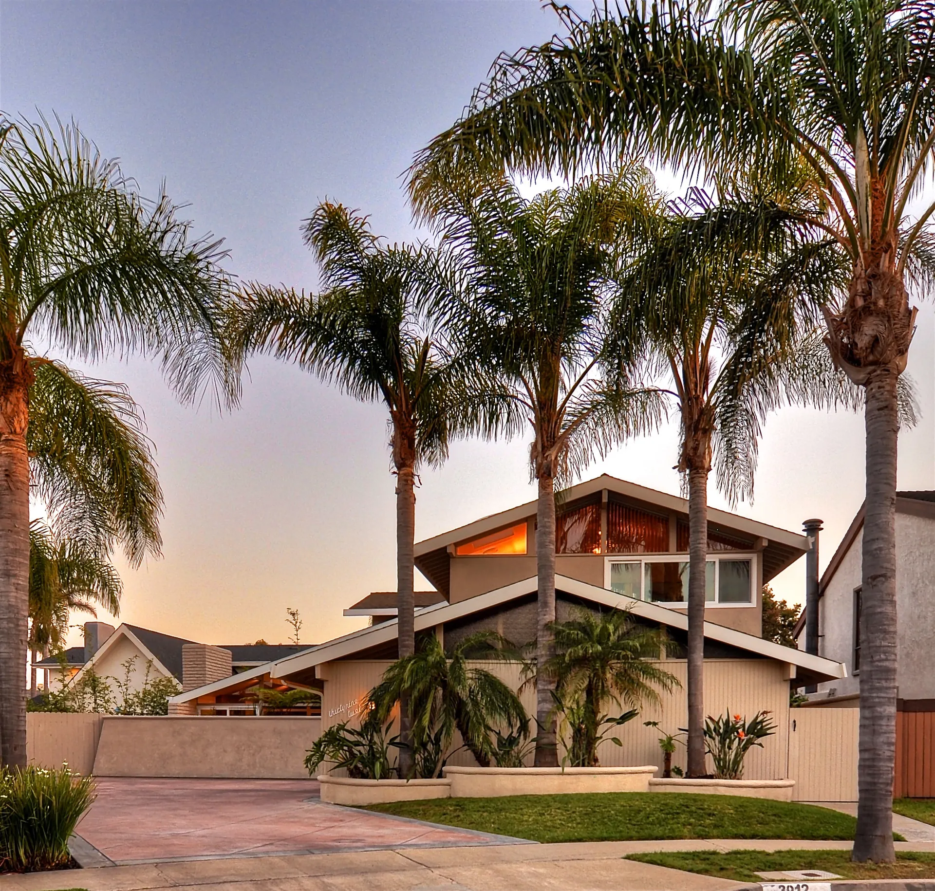 Twilight exterior of a Huntington Harbour home framed by palms, a Ratowsky Group listing.